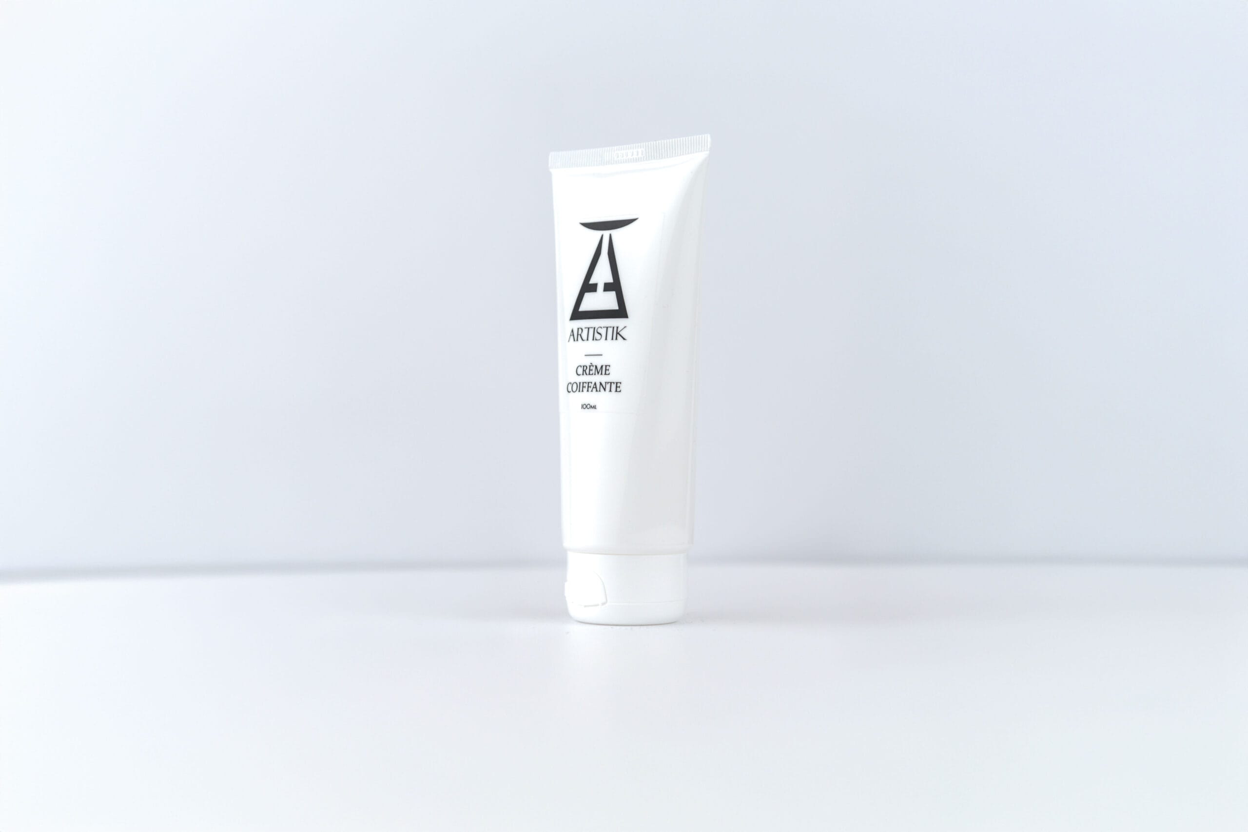 Crème coiffante ARTISTIK, tube légèrement pivoté sur fond blanc